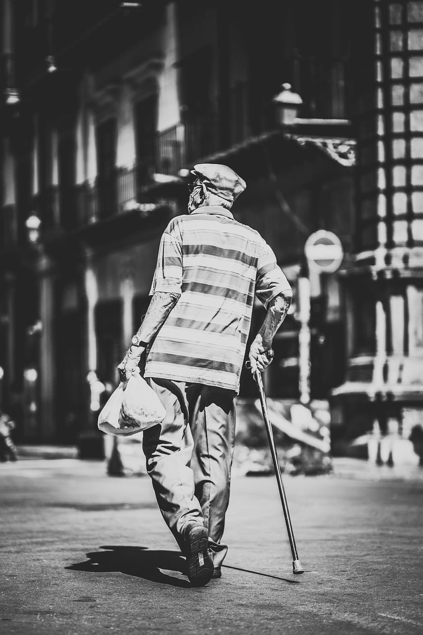 Sénior marchant avec une canne illustrant la perte de mobilité et le besoin d'accompagnement chiropratique.