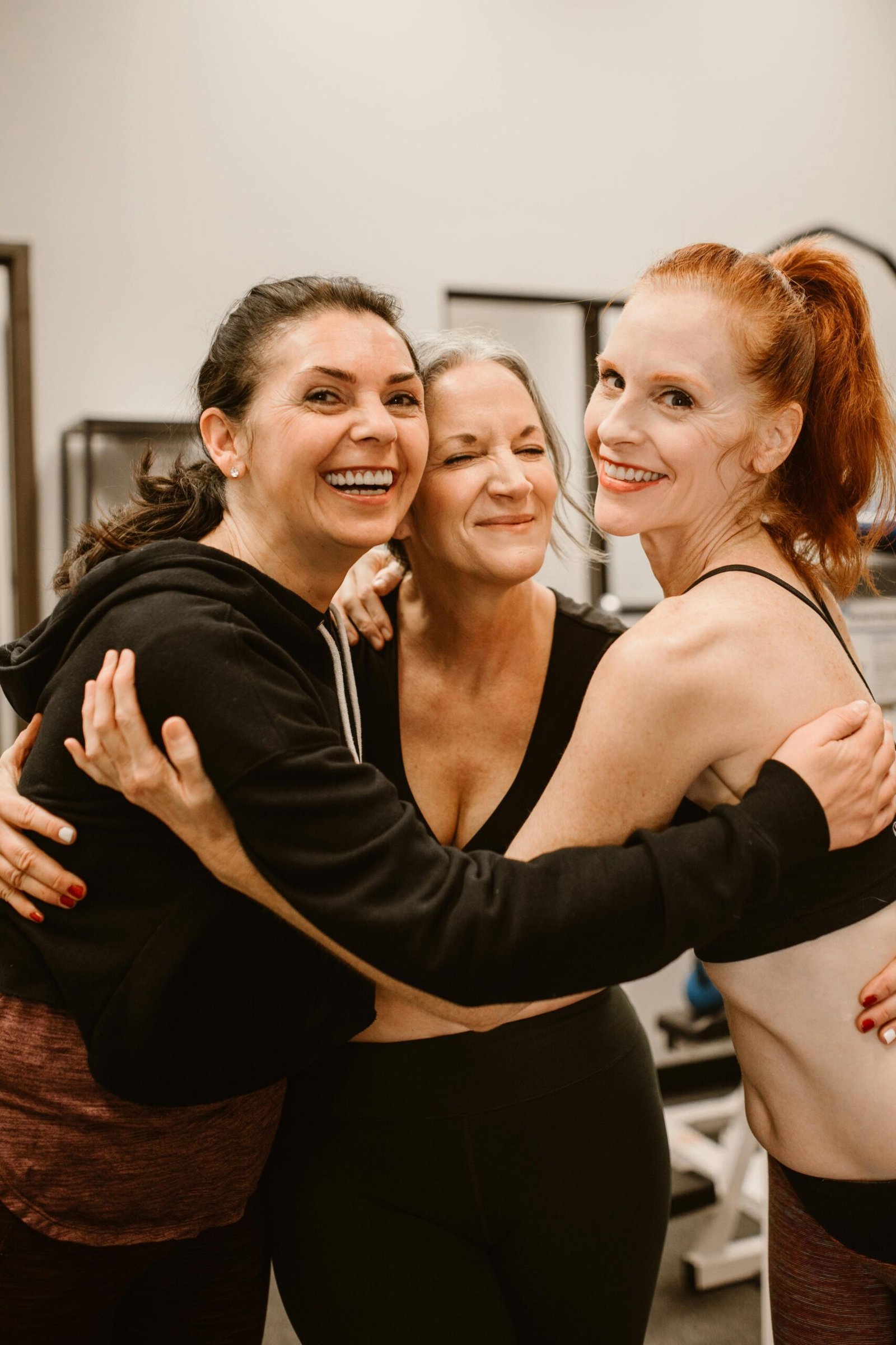 Trois femmes d'âges différents s'enlaçant pour illustrer l'accompagnement de la santé féminine à chaque étape de la vie.
