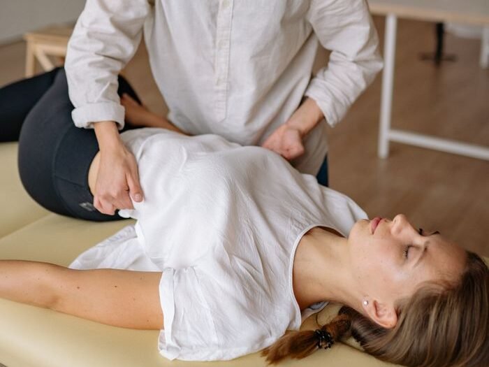 Chiropracteur effectuant une mobilisation douce du bassin et de la colonne lombo-sacrée chez une patiente